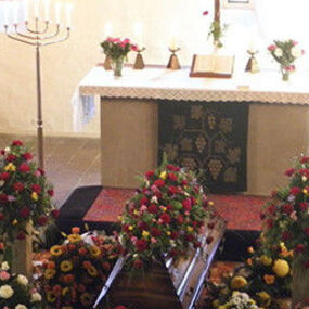 Blumengeschmückter Sarg in einer Kirche vor dem Altar bei einer Trauerfeier.