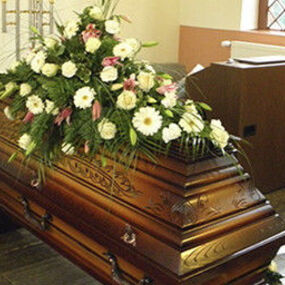 Holzsarg mit Blumenschmuck in einer Kapelle, Trauerfeier Bestattung Begräbnis.