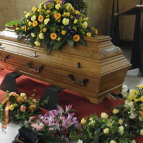 Sarg mit Blumenarrangements und Trauerfloristik bei einer Bestattung in einer Trauerhalle.